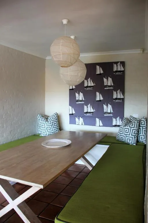 Built-in dining nook with a wooden table, green bench seating, and pendant lanterns