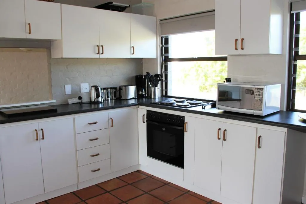White fitted kitchen with a built-in oven, gas hob, and microwave