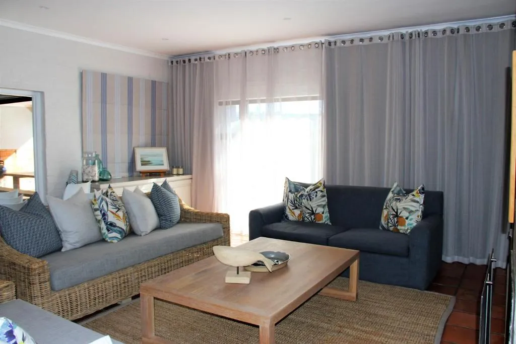 Living room with a rattan sofa, navy two-seater couch, and sheer curtains