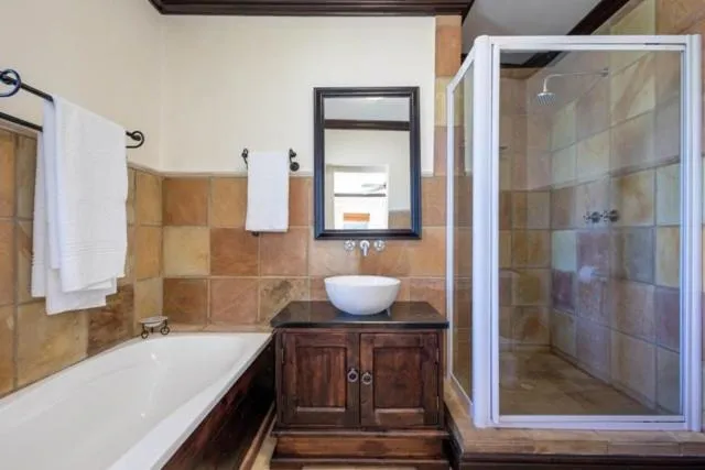 En-suite bathroom with a bath, vessel basin on a wood vanity and glass shower cubicle