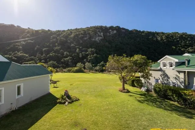 Communal lawn between villas backing onto a wooded sandstone cliff and hillside