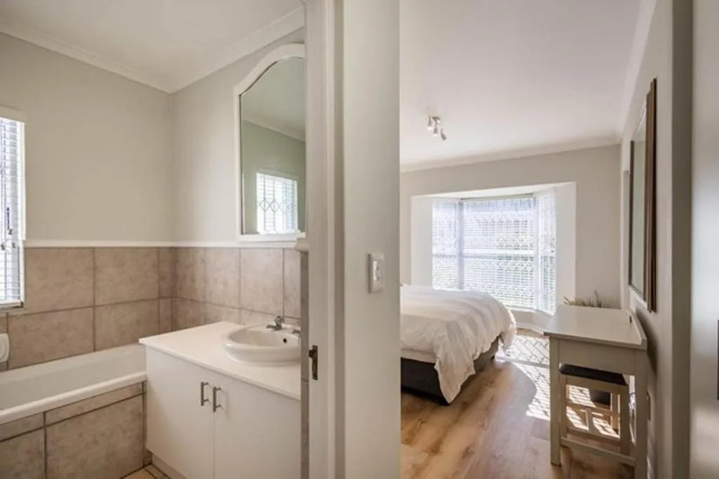 En-suite bathroom with freestanding tub and vanity, opening through to a second bedroom with bay window