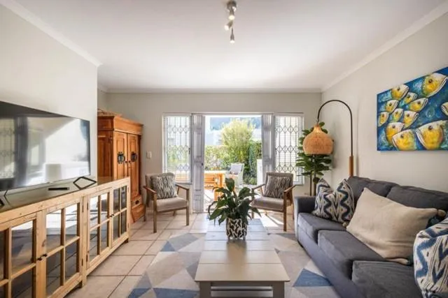 Living room with grey sofa, colourful fish artwork and doors opening onto a shaded patio