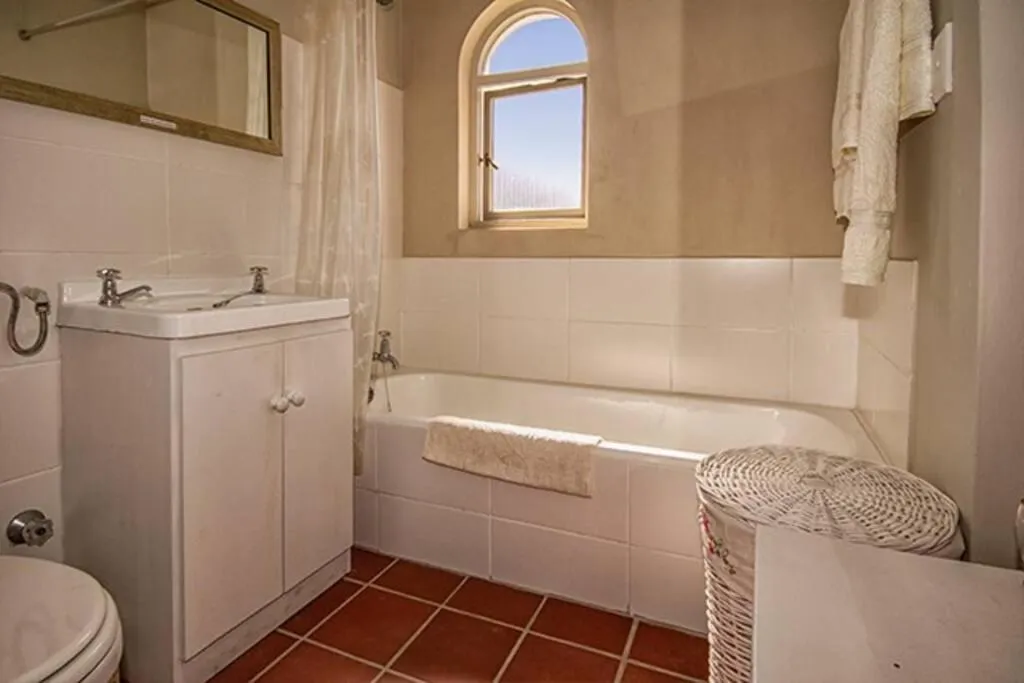 Bathroom with a corner bath, twin-basin vanity and an arched window