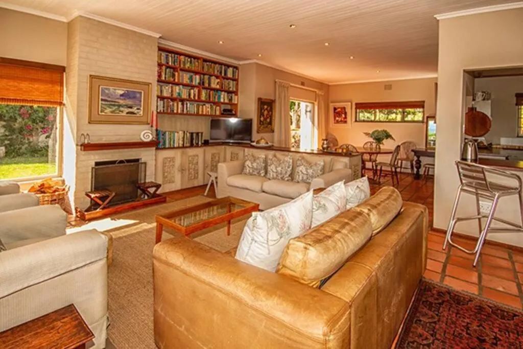 Open-plan living room with a brick fireplace, built-in bookshelves and leather sofas