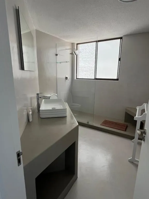 Bathroom with a vessel sink, glass-walled shower and window