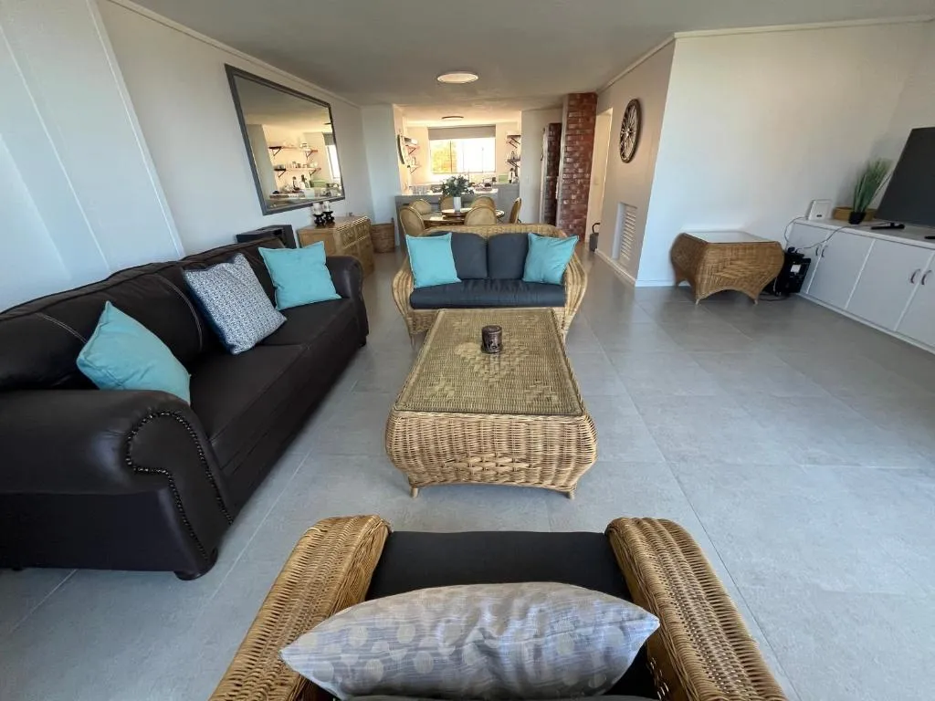 Living room with a dark leather sofa, wicker coffee table and brick pillar