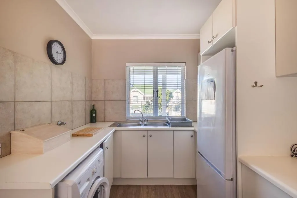 Kitchenette nook with a washing machine, fridge and window over the estate
