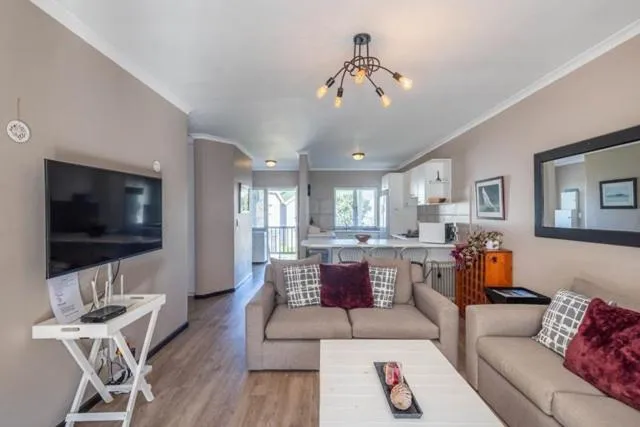 Open-plan living room with a wall-mounted TV and a view through to the kitchen