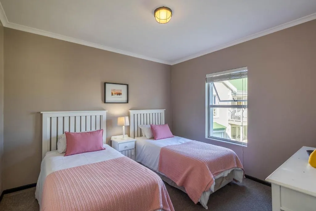 Twin bedroom with pink bedspreads and a window onto the neighbouring rooftops