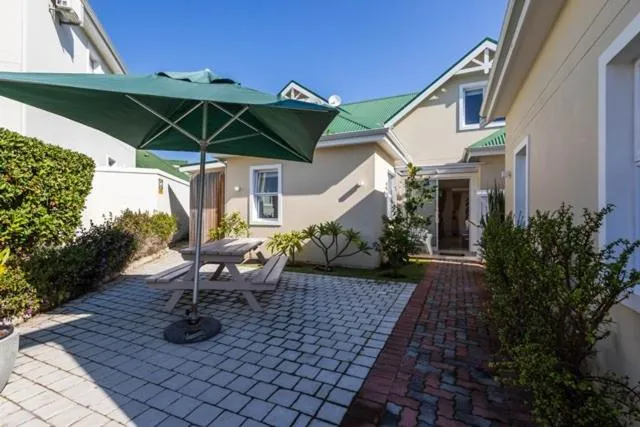 Paved courtyard patio with a wooden picnic table and umbrella beside the house