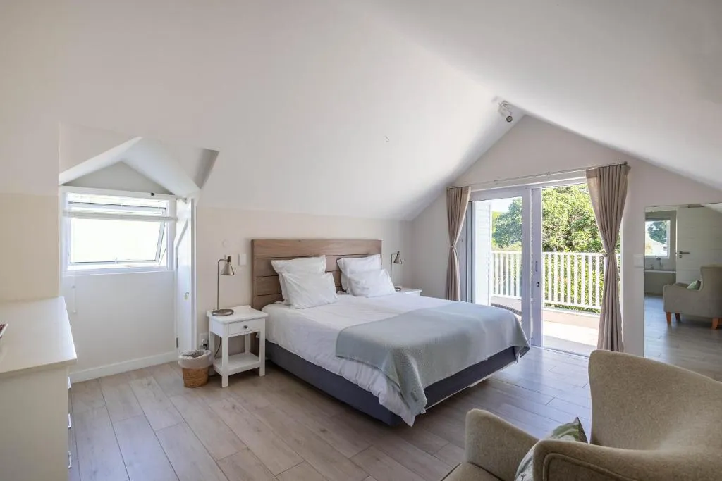 Loft bedroom with a vaulted ceiling and French doors onto a tree-lined balcony