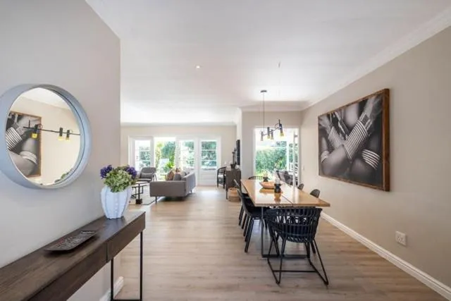 Open-plan dining area with a round wood table seating six, leading into the living room
