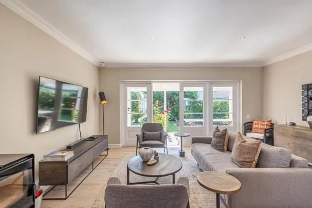 Living room with grey sofas, a wall-mounted TV, and French doors onto the garden