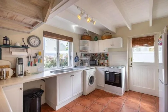 Farmhouse-style kitchen with exposed beams, gas stove and front-loading washing machine