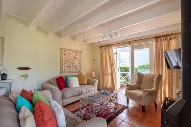 Living room with exposed beam ceiling, colourful scatter cushions and French doors onto the garden