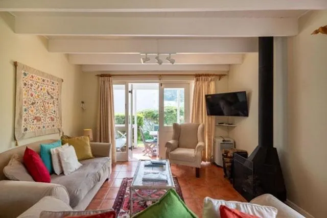 Second view of the living room showing the wood-burning stove, wall-mounted TV and patio doors