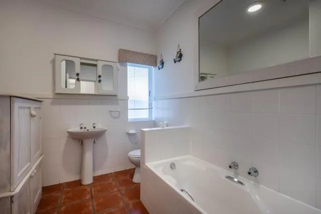 Bathroom with a built-in bath, pedestal basin, and a mirrored medicine cabinet