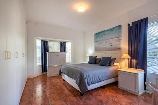 Bedroom with a bay window, navy curtains, and a coastal painting above the bed
