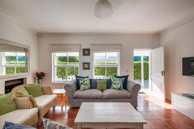 Living room with a fireplace and wicker chair, doors opening onto the garden