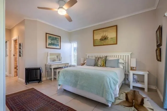 Bedroom with a queen bed, ceiling fan, and nautical artwork above the headboard