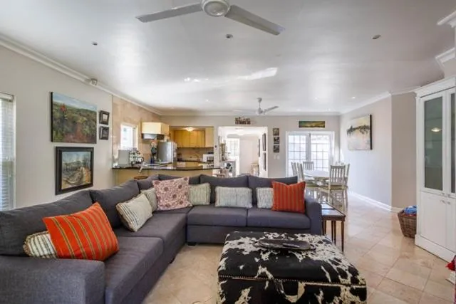Open-plan lounge with a grey sectional sofa, cowhide ottoman, and dining area beyond