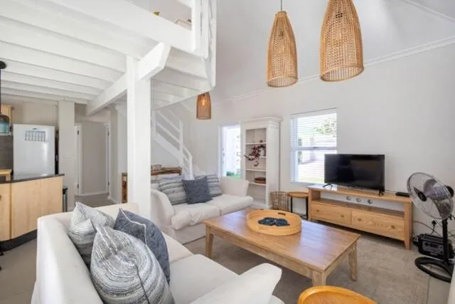 Open-plan living room with double-volume ceiling, mezzanine loft and rattan pendant lights