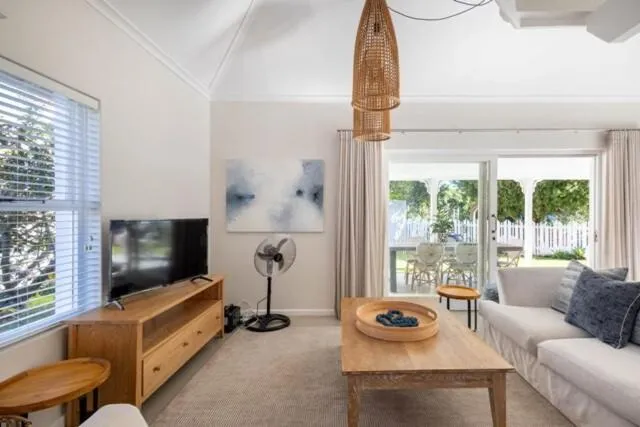Second lounge with TV opening onto a covered veranda and picket-fenced garden