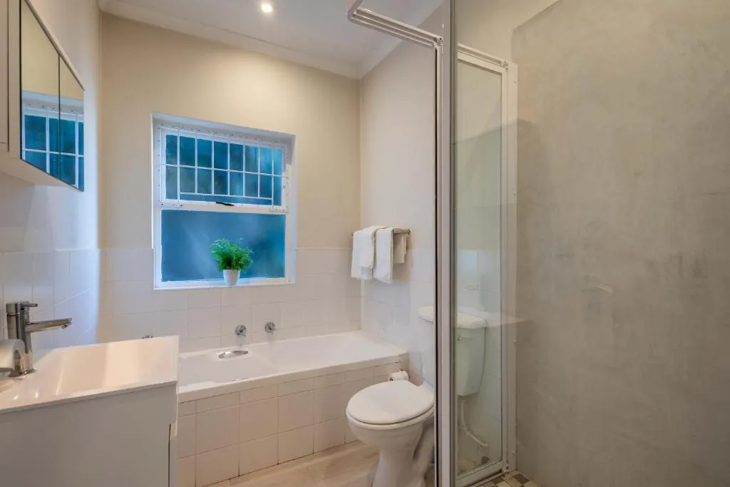 Bathroom with a full bathtub, separate glass shower stall and a sash window over the tub