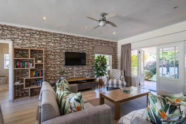 Second living room with a stacked-stone wall, built-in bookshelf and doors open to the garden