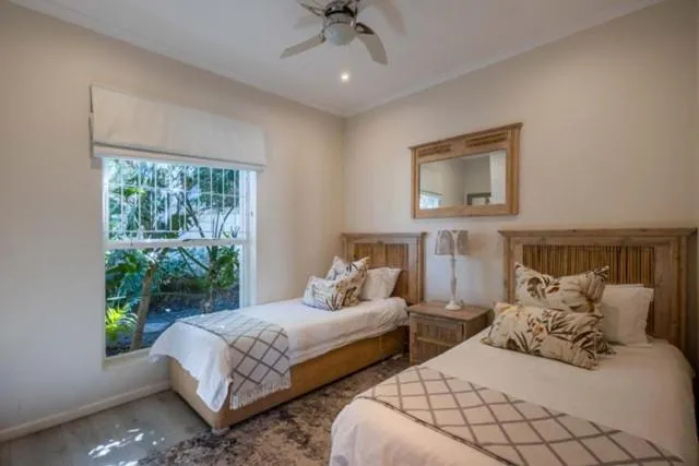 Twin bedroom with matching timber headboards and a garden view through aluminium windows