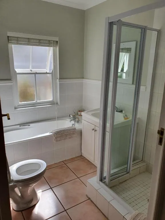 Family bathroom with a corner shower, bathtub and toilet finished in cream tile
