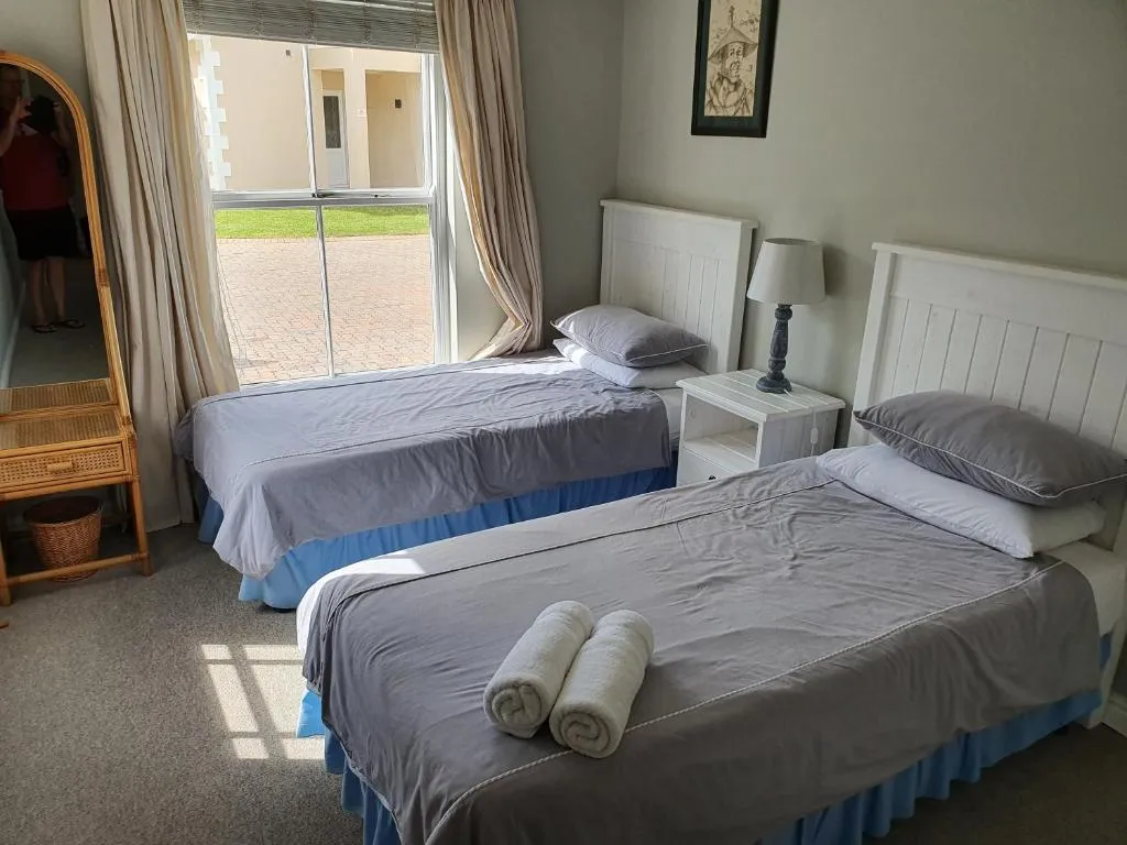 Twin bedroom with white bed frames, pastel blue linen and a window looking onto the courtyard