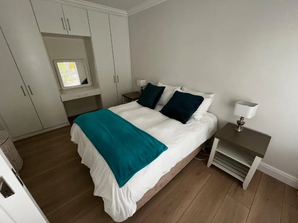 Bedroom with fitted wardrobes, a dressing table and a teal throw on the bed