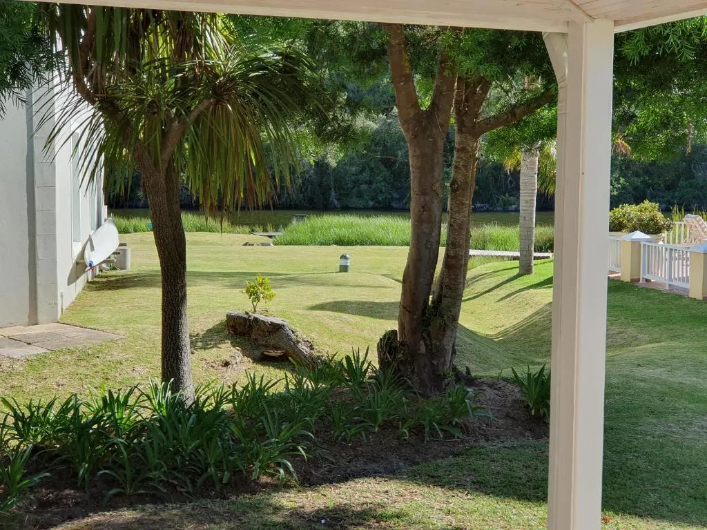 Covered patio looking over a lawned garden to reeds along the river