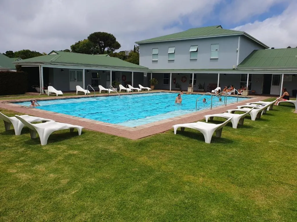 Shared estate swimming pool with sun loungers and guests swimming, clubhouse behind
