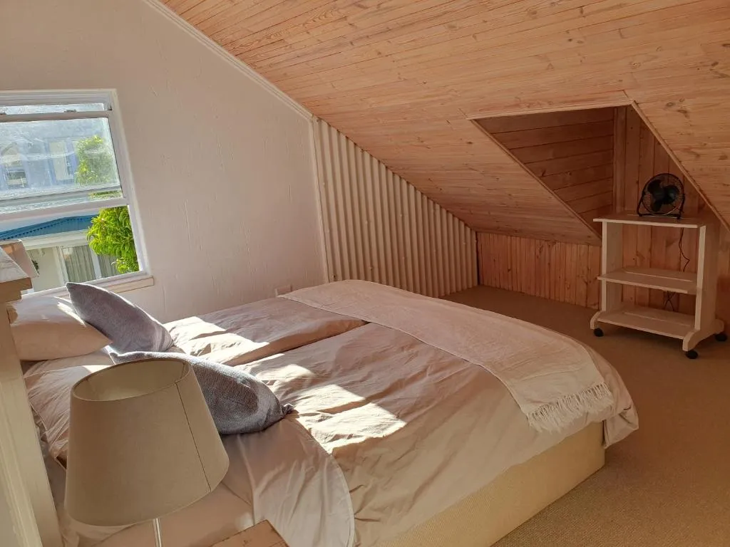 Loft bedroom with sloped timber-clad ceiling and a double bed under the eaves
