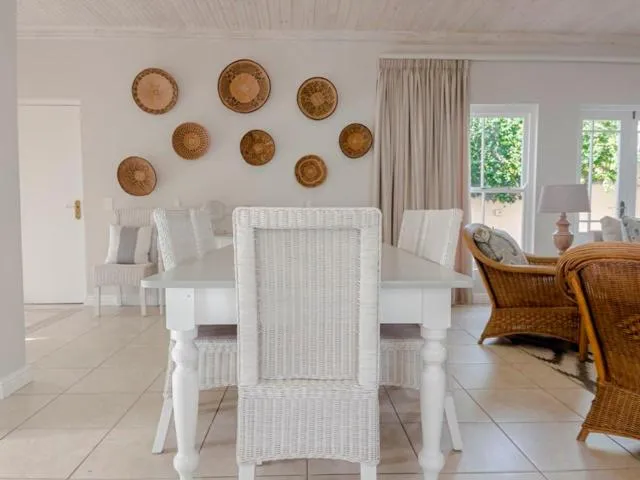 Dining area with a white wooden table, wicker chairs and woven baskets on the wall