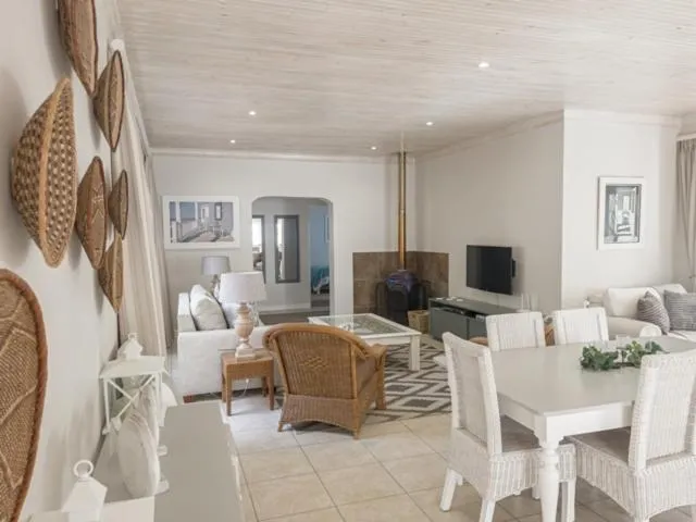 Living room with a built-in wood-burning fireplace, TV and rattan armchairs under a raftered ceiling