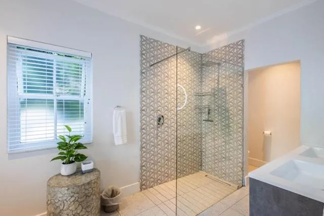 Bathroom with a patterned-tile walk-in glass shower and a freestanding stone side table