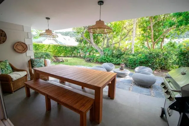 Covered outdoor dining patio with pendant lighting, stone tables and a gas braai