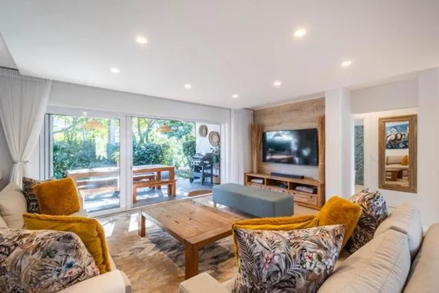 Living room opening onto a garden deck with a second braai and outdoor dining table