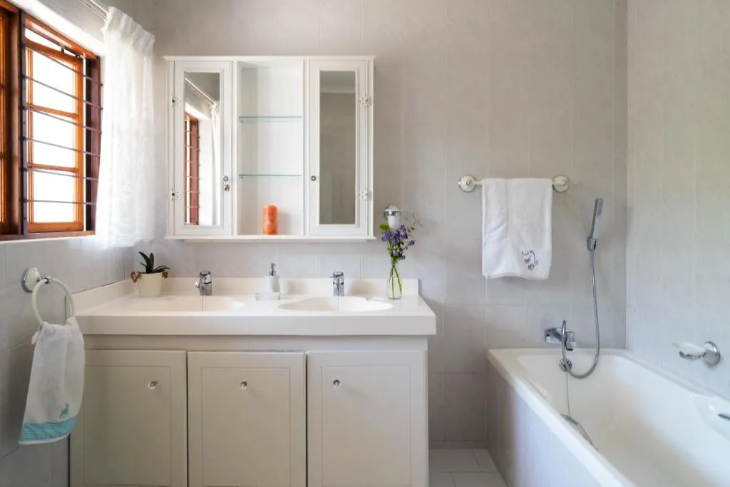 Bathroom with a double vanity, built-in bathtub and a wood-framed window