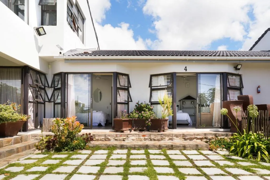 Garden-facing bedroom suites opening through French doors onto a stone garden path with flowering aloes