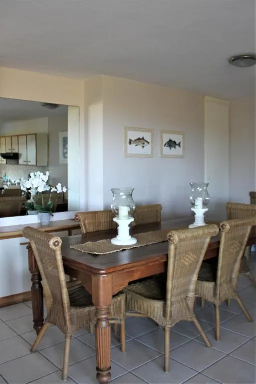 Wooden dining table seating six with wicker chairs, opening through to the kitchen