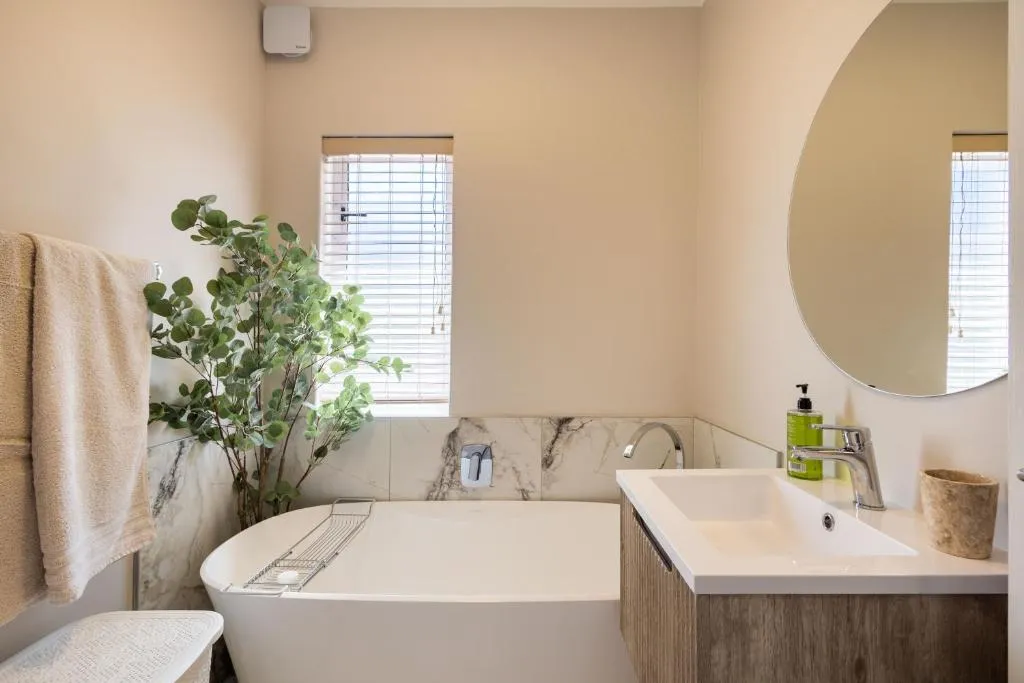 Ensuite bathroom with a freestanding oval bathtub and round wall mirror