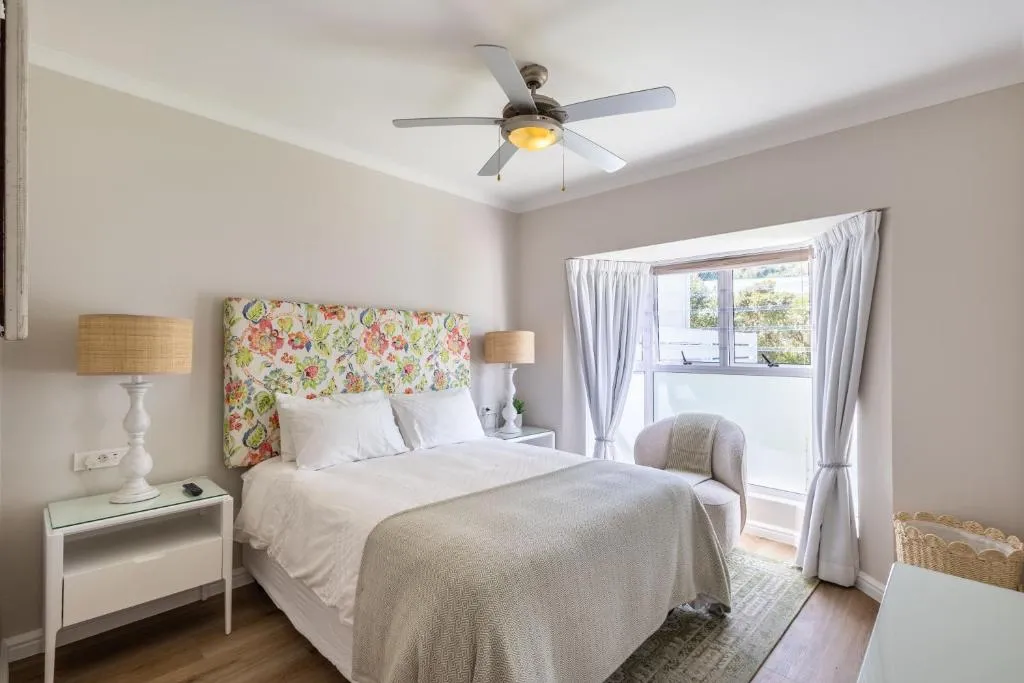 Bedroom with a floral upholstered headboard and curtained window onto a balcony