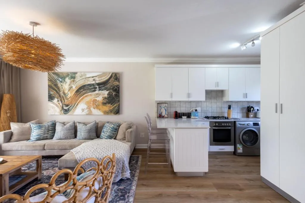 Open-plan kitchen with white cabinetry, gas hob and a rattan pendant light overhead
