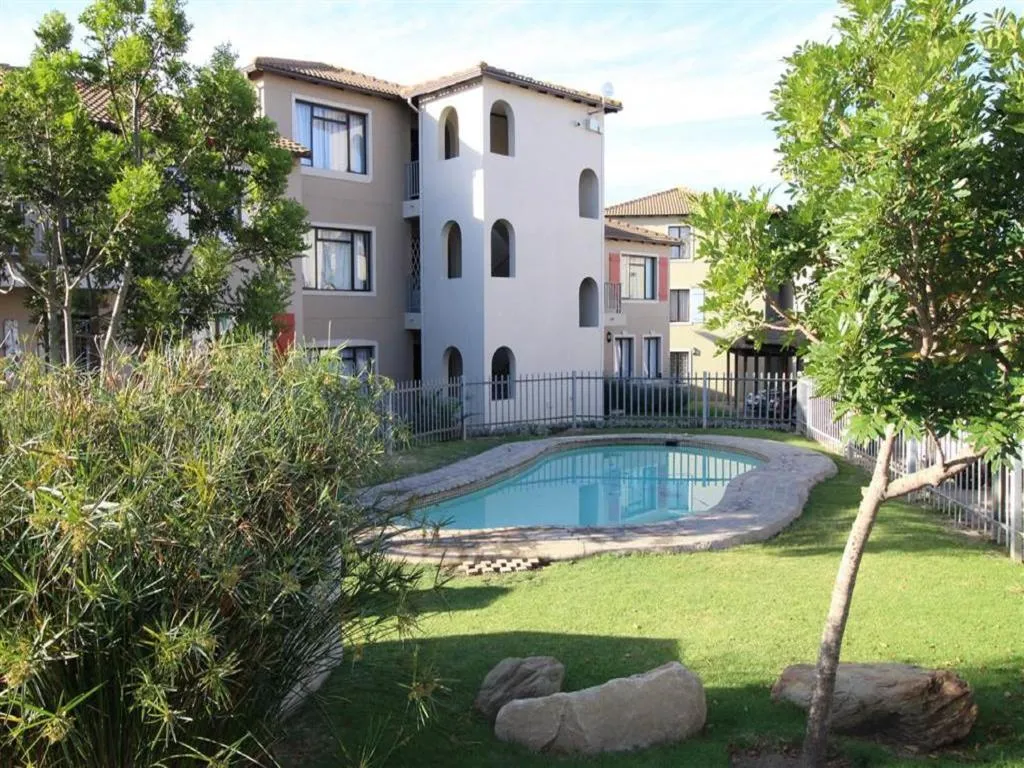 Complex exterior showing the shared communal swimming pool and garden at Santini Village