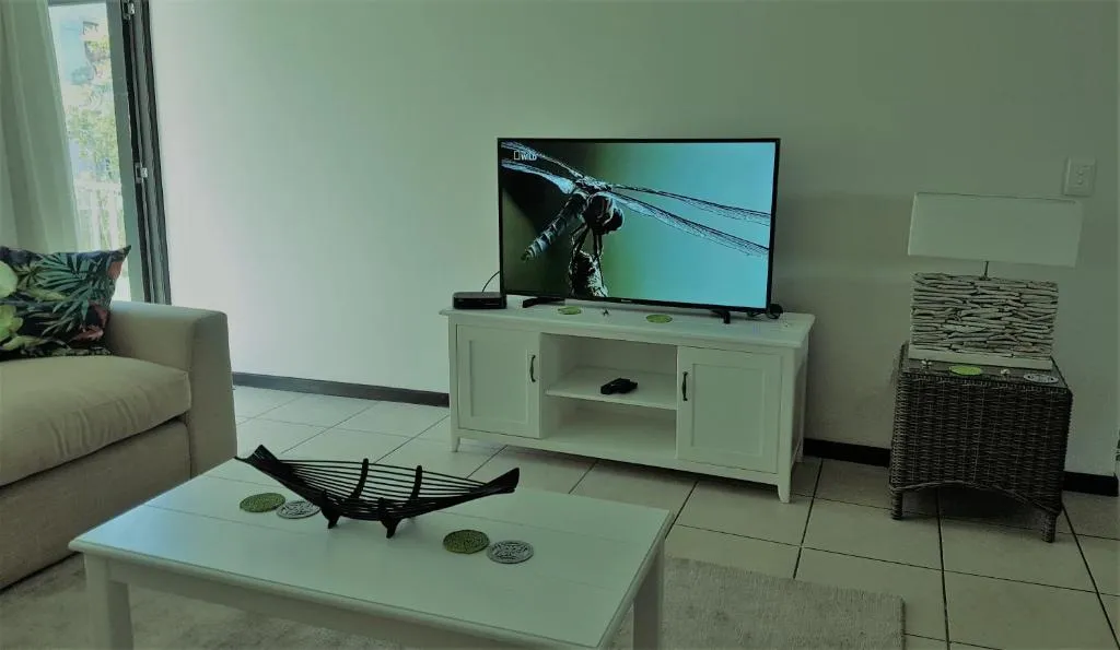 Living room corner with wall-mounted TV, sideboard and rattan side table